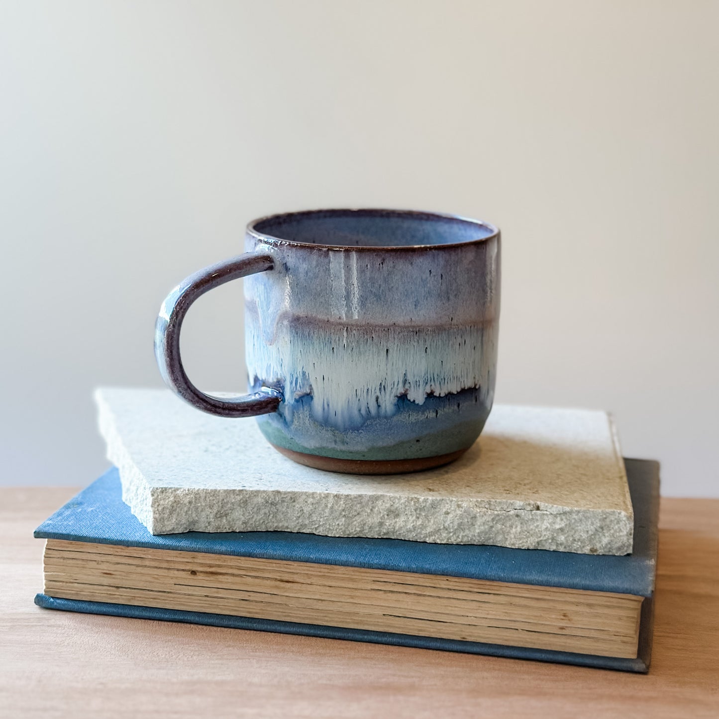 Purple and blue ceramic mug on top of a tile with a plain background