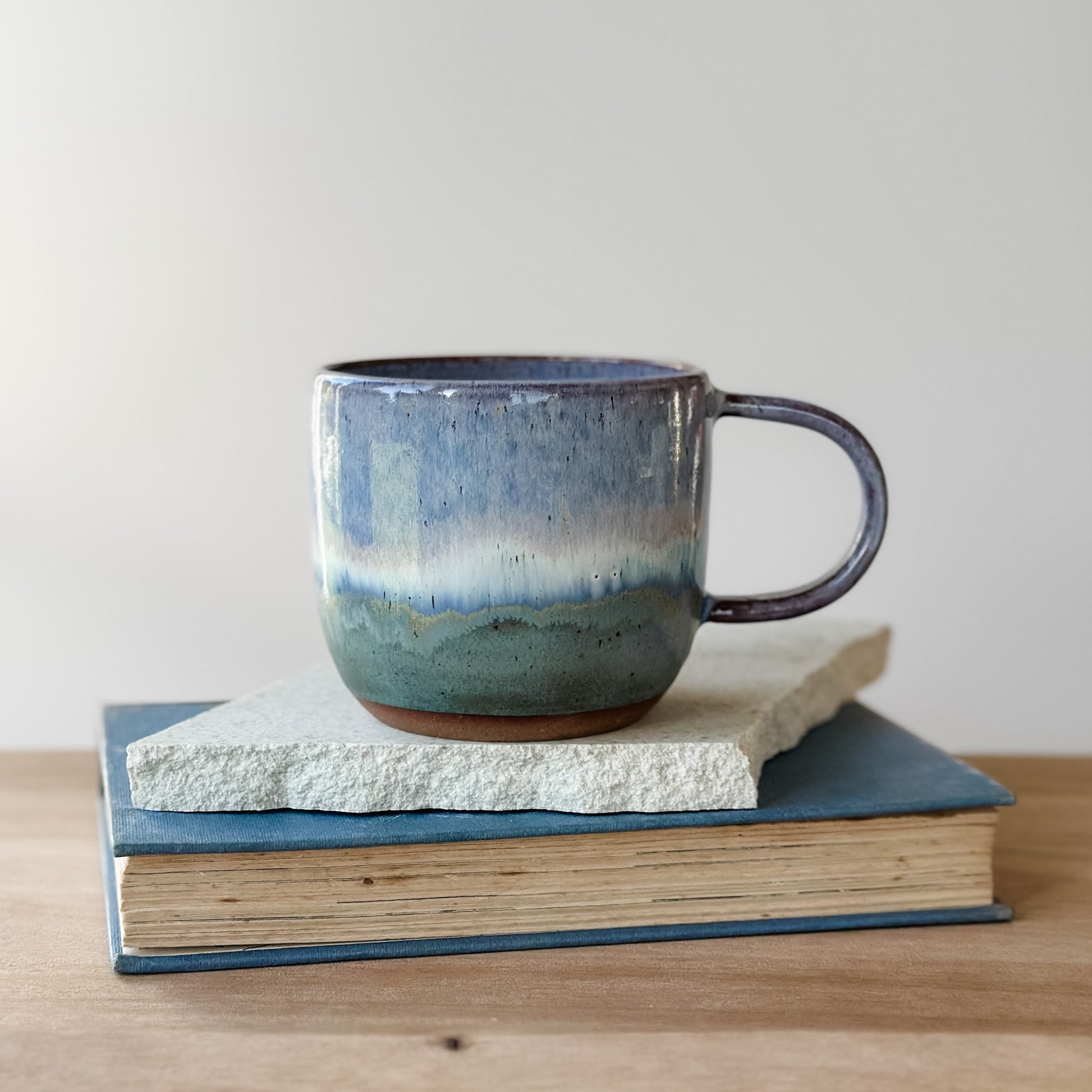 Ceramic mug with a gradient finish on top of a tile and a book