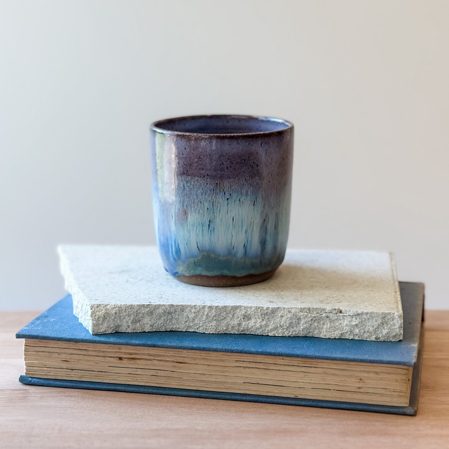 Ceramic tumbler on top of two books with a plain background