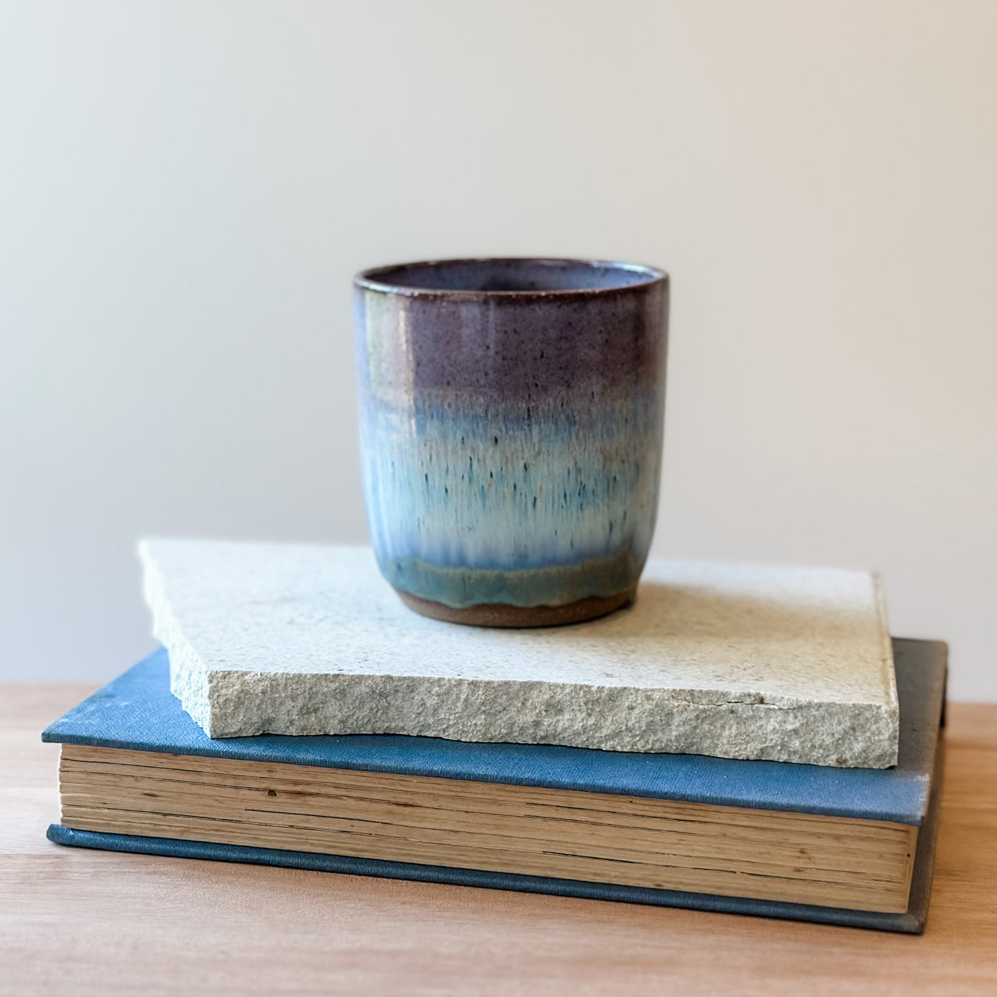 Ceramic tumbler with a purple and blue gradient on top of a wooden surface