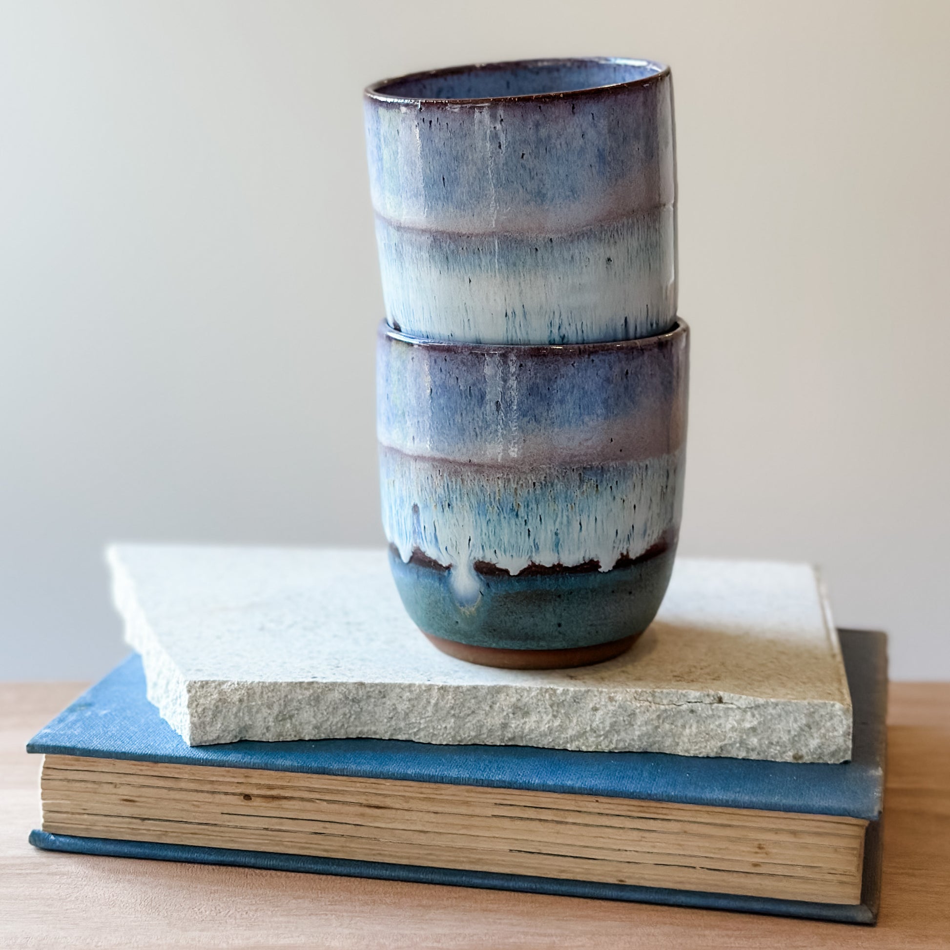 Stacked ceramic cups with a textured finish on top of books