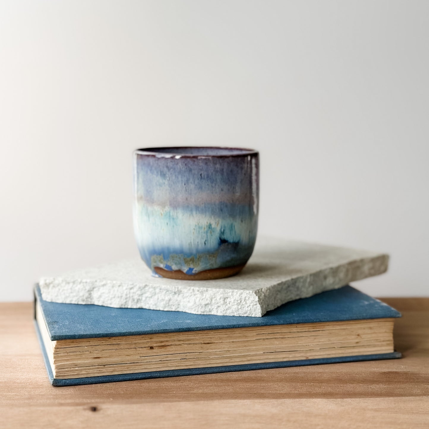 Ceramic mug with blue and purple glaze on top of a book