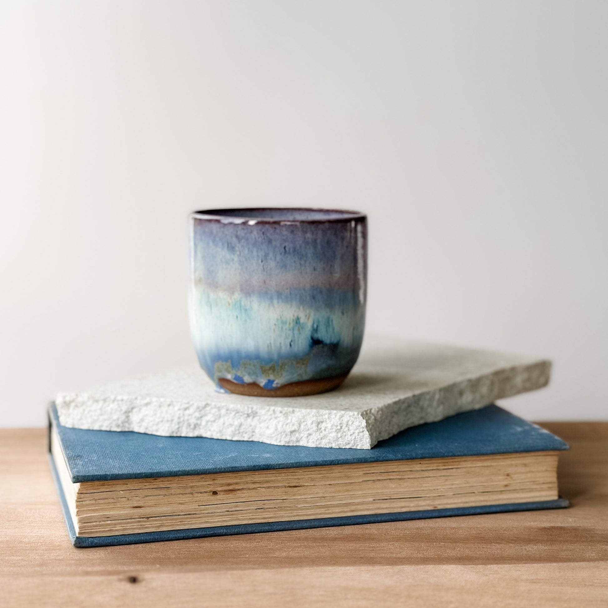 Ceramic mug with blue and purple glaze on top of a book