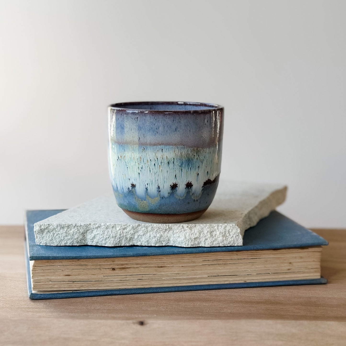 Ceramic mug with blue and brown glaze on top of a book