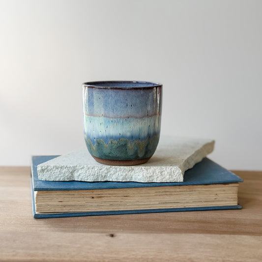 Blue ceramic cup on a stack of books with a plain background