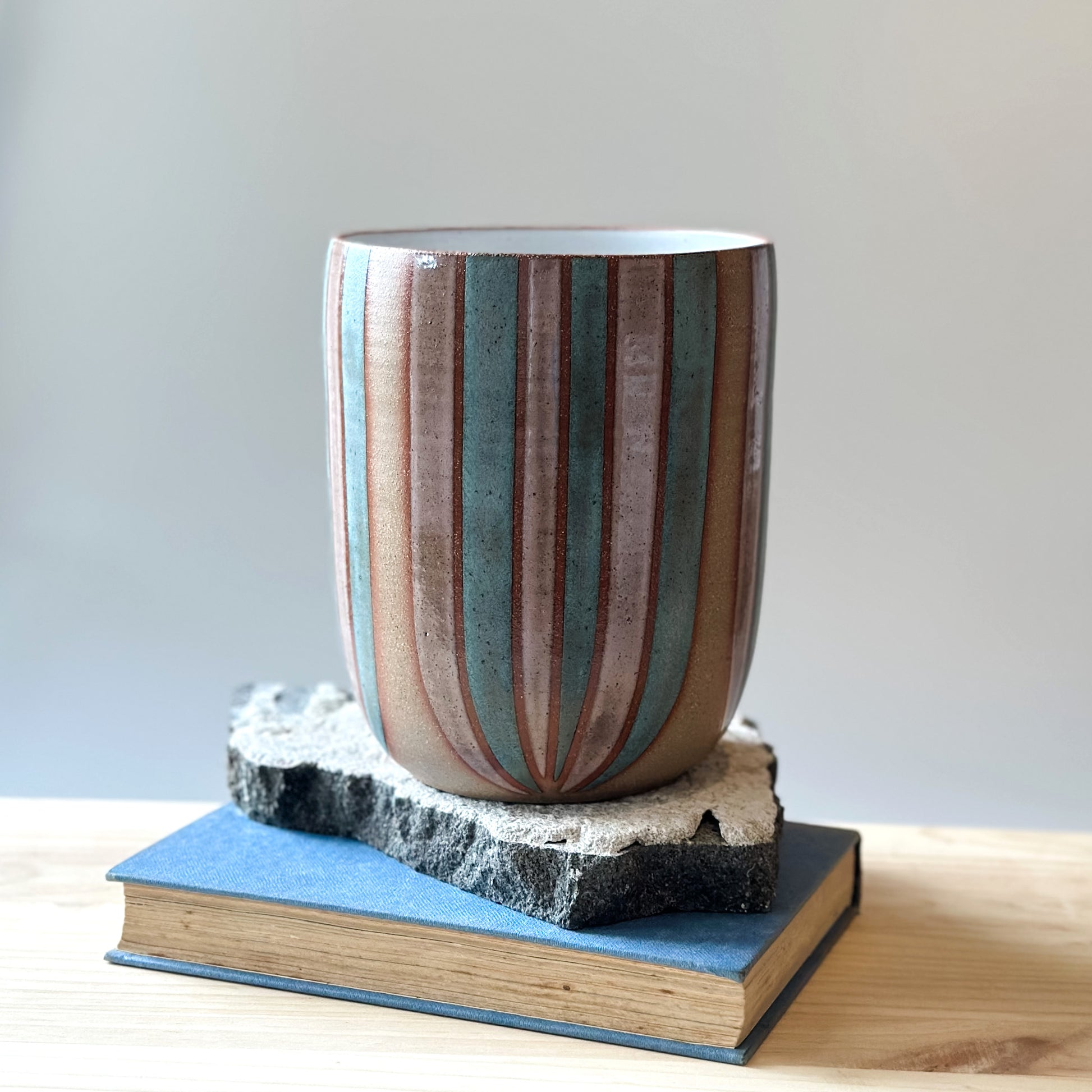 A front view of a large handmade ceramic bouquet vase sitting on a table. The ceramic vase is hand-painted in blush pink and denim blue glaze.
