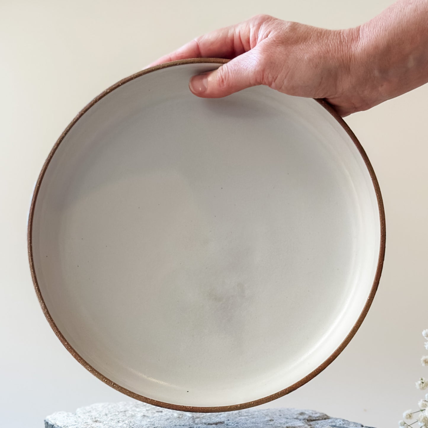 An interior view of a Coastal Handmade Ceramic Platter. The platter has a white interior. One hand is holding the platter.