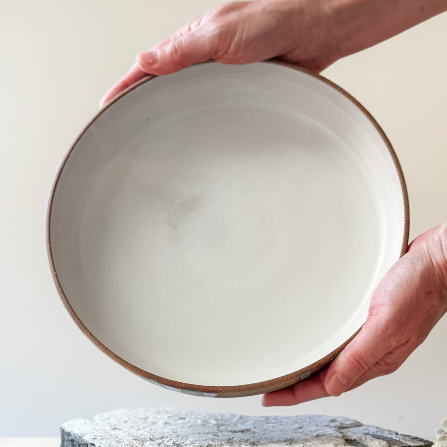 An interior view of a Coastal Handmade Ceramic Platter. The platter has a white interior. Two hands are holding the platter.