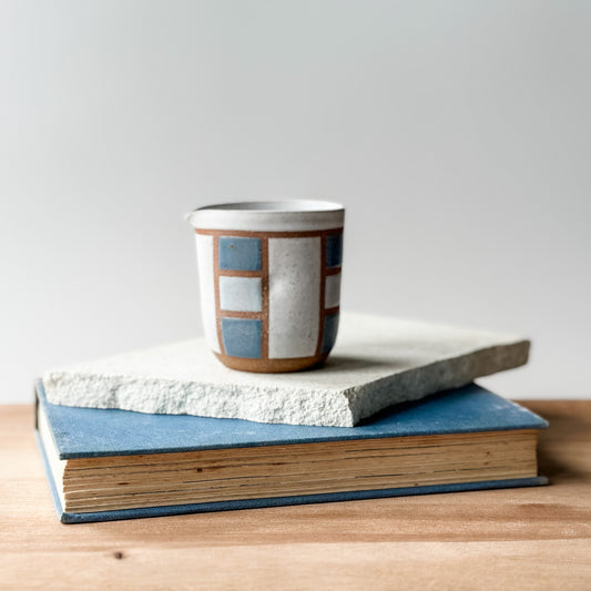 Ceramic mug with geometric pattern on top of a book