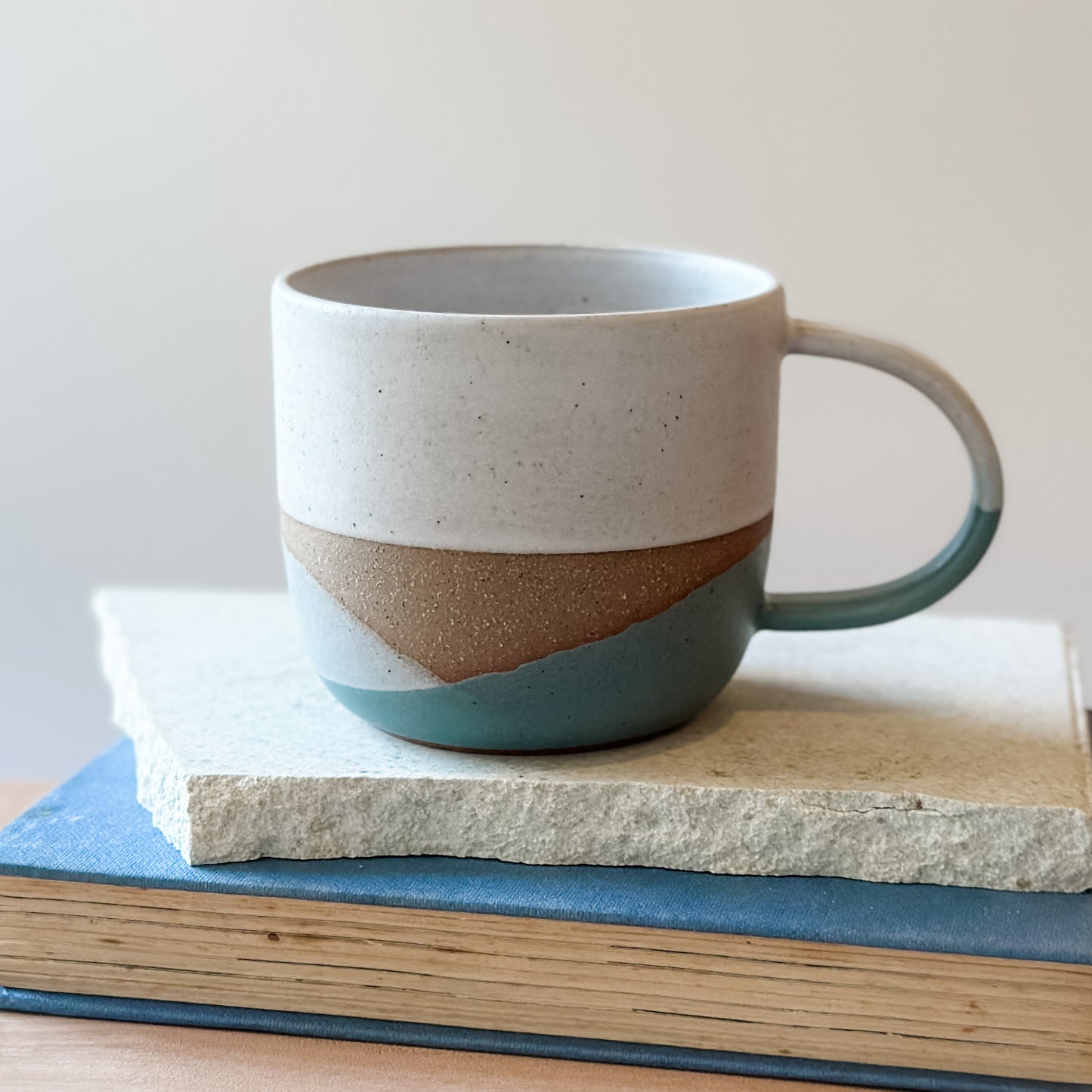 Ceramic mug with a coastal design on a tile and a book