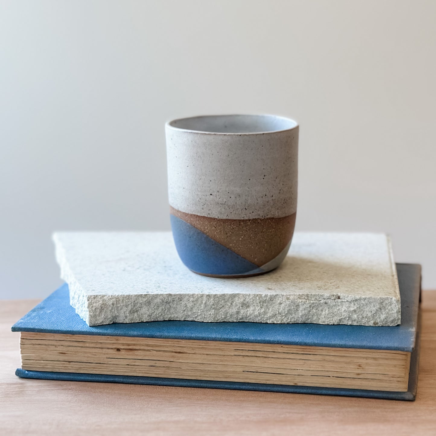 Ceramic cup with two-tone design on top of a book