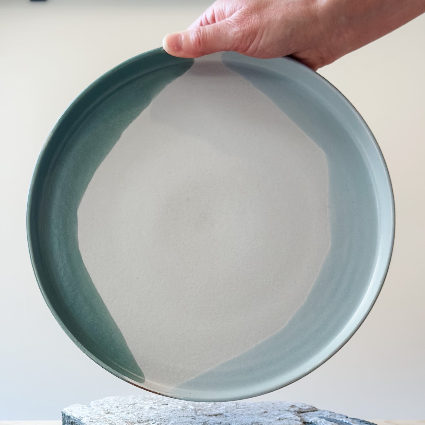An inside view of the large Tidal Handmade Ceramic Platterbeing held by one hand. The handmade platter is green, blue-grey and white.