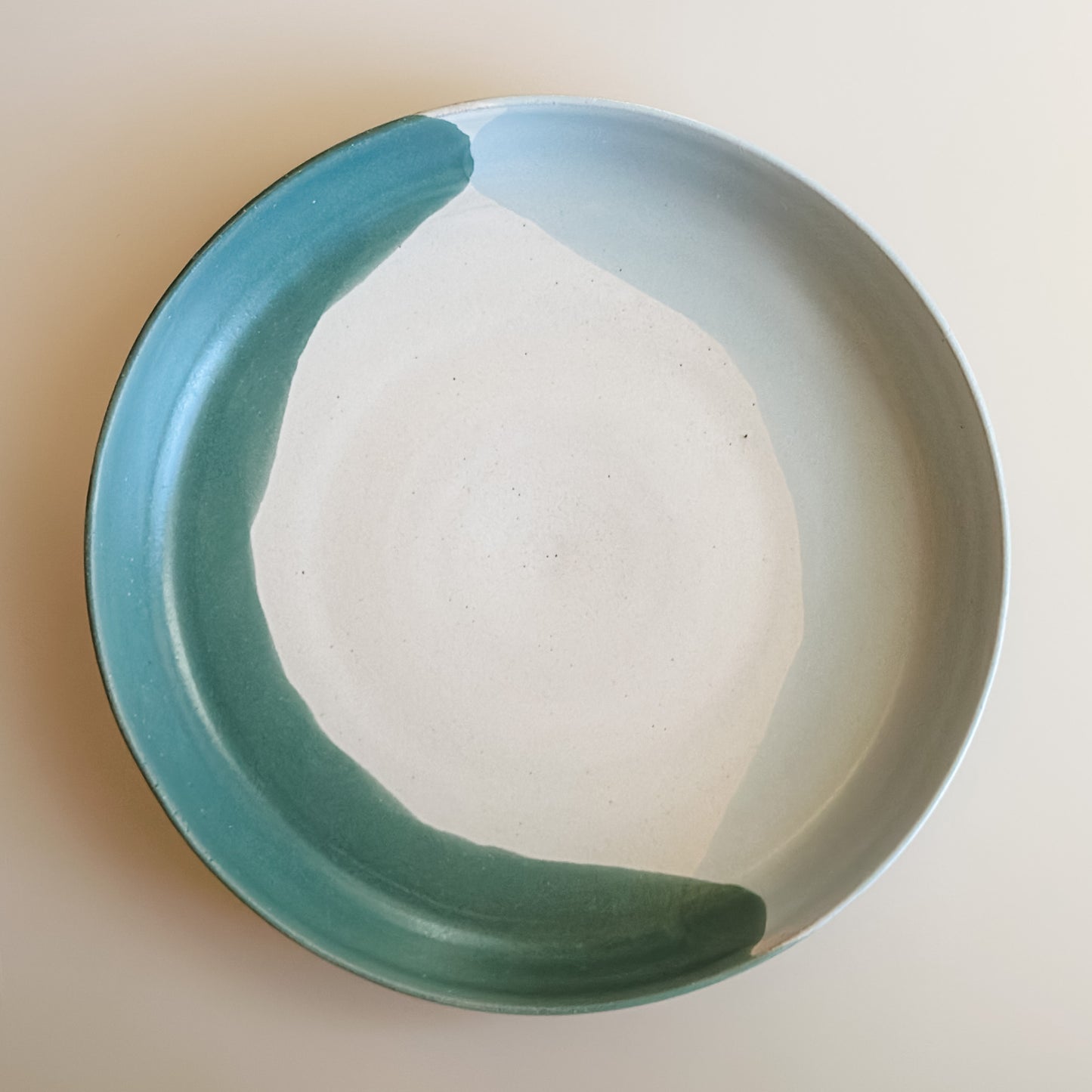 A aerial view of the interior of the large Tidal Handmade Ceramic Serving Dish. The dish is green, white and blue-grey and sits on a cream background.