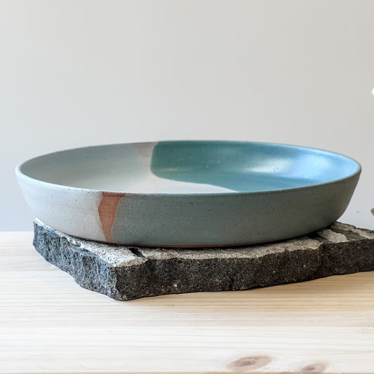 A front view of the medium Tidal Handmade Ceramic Dish in a green, white and blue-grey glaze. The ceramic dish sits on a cream background.