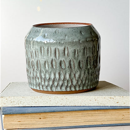Textured ceramic pot on a stack of books with a plain background