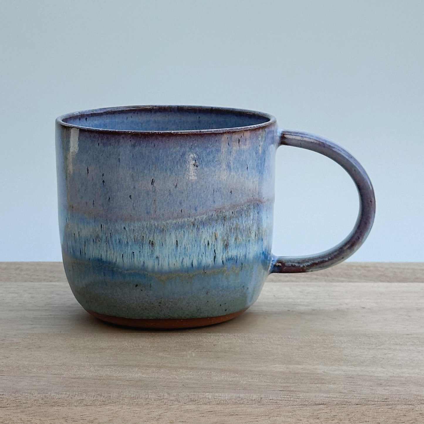 Blue ceramic mug on a wooden surface with a light blue background
