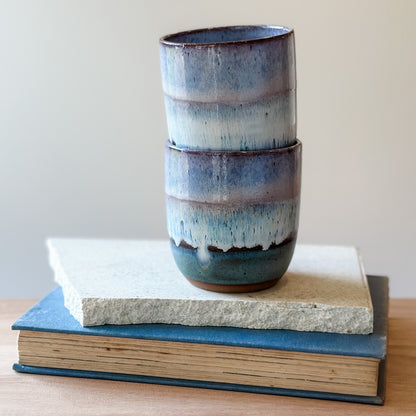 Stacked ceramic cups with a textured finish on top of books