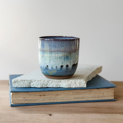 Ceramic mug with blue and brown glaze on top of a book