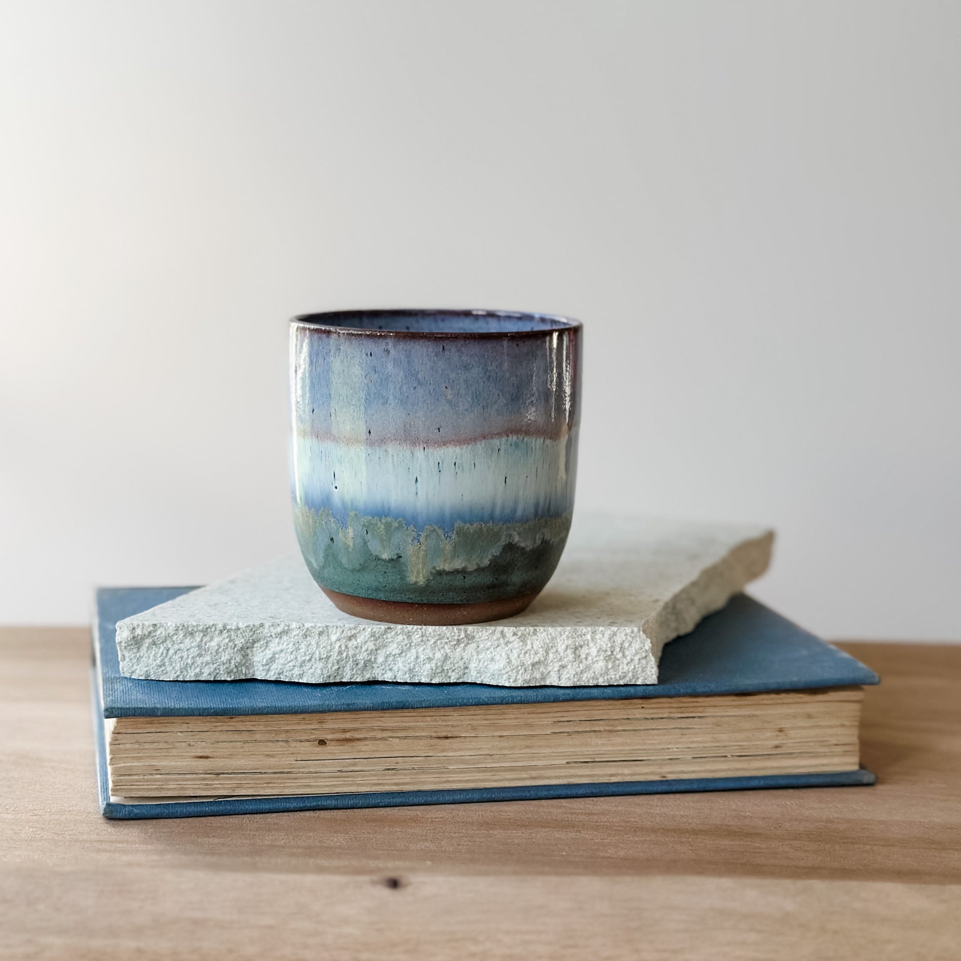 Ceramic cup with blue and purple glaze on a stack of books