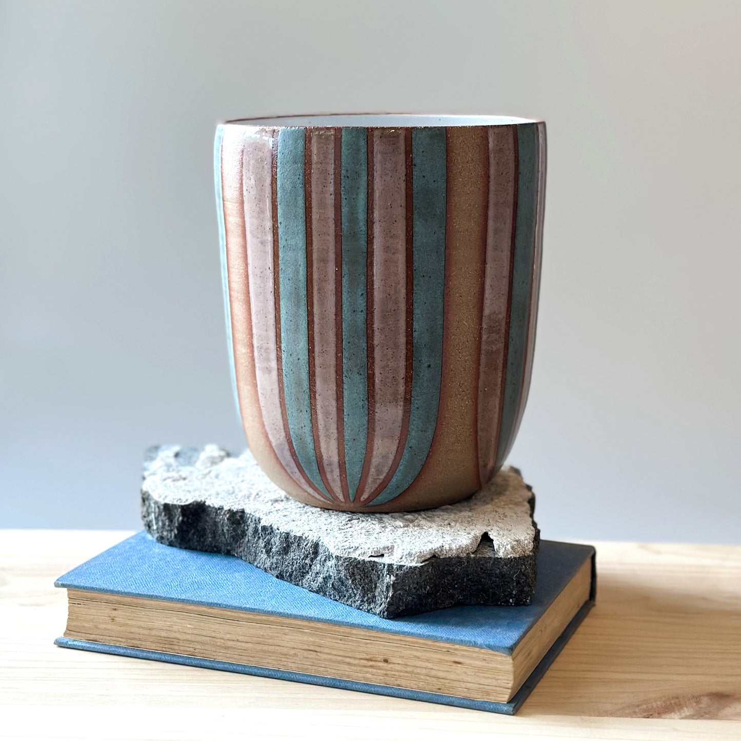 A large handmade ceramic bouquet vase sits on a table. The ceramic vase is hand-painted in blush pink and denim blue glaze. 