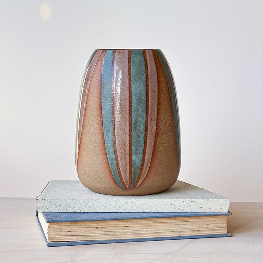 Large vase with striped design on a tile and book