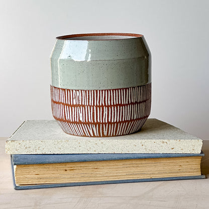 Ceramic planter pot with two books on a light wooden surface