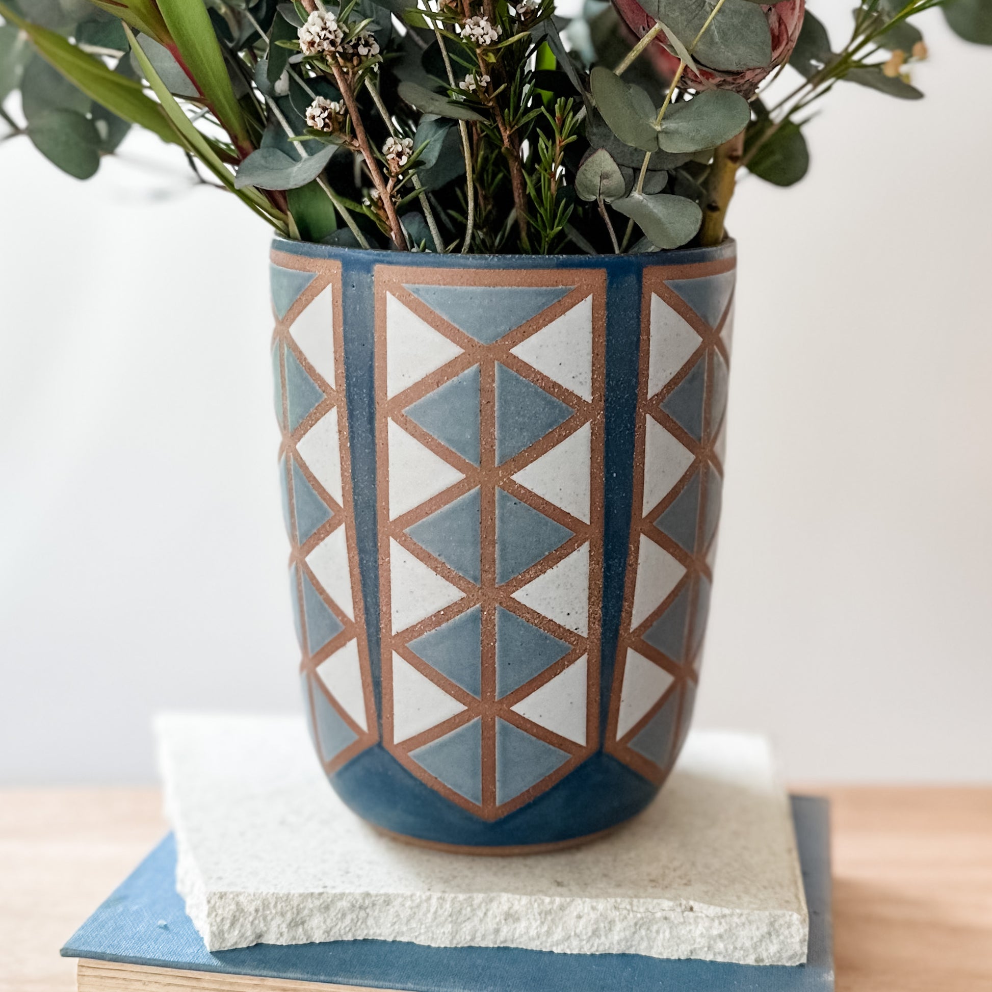 Ceramic vase with geometric pattern with flowers on a wooden surface.