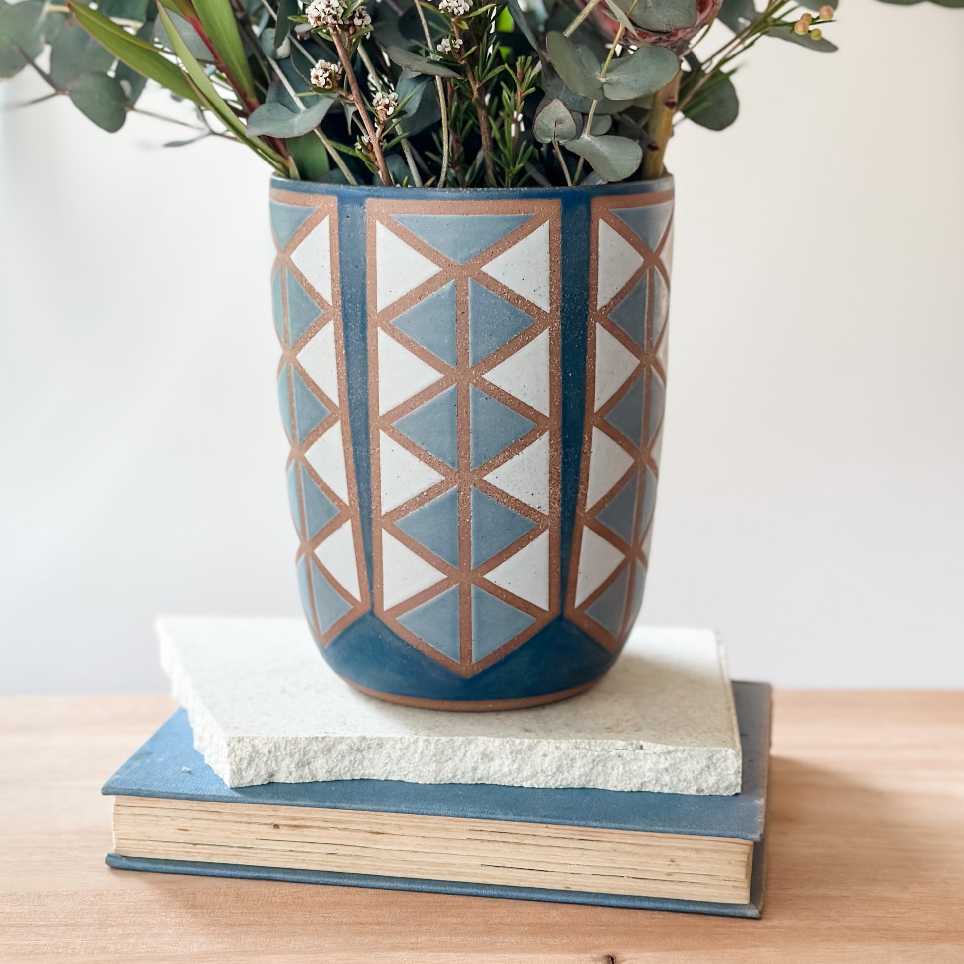 Decorative ceramic vase with geometric pattern on a stack of books