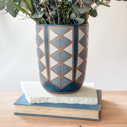 Decorative ceramic vase with geometric pattern on a stack of books