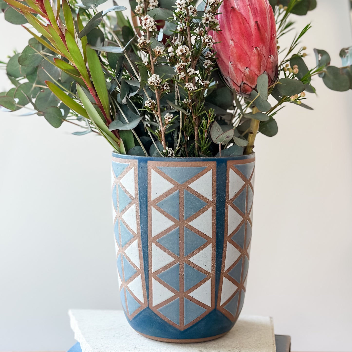 Decorative vase with geometric pattern filled with flowers on a white surface