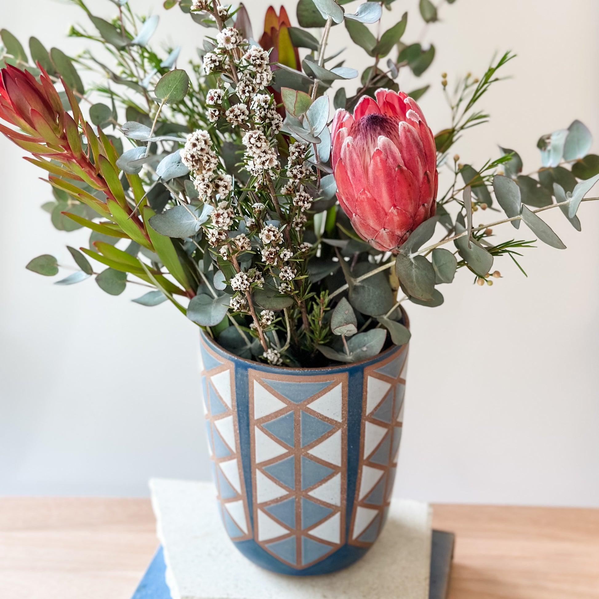 Bouquet of flowers in a geometric-patterned vase on a light surface with a neutral background