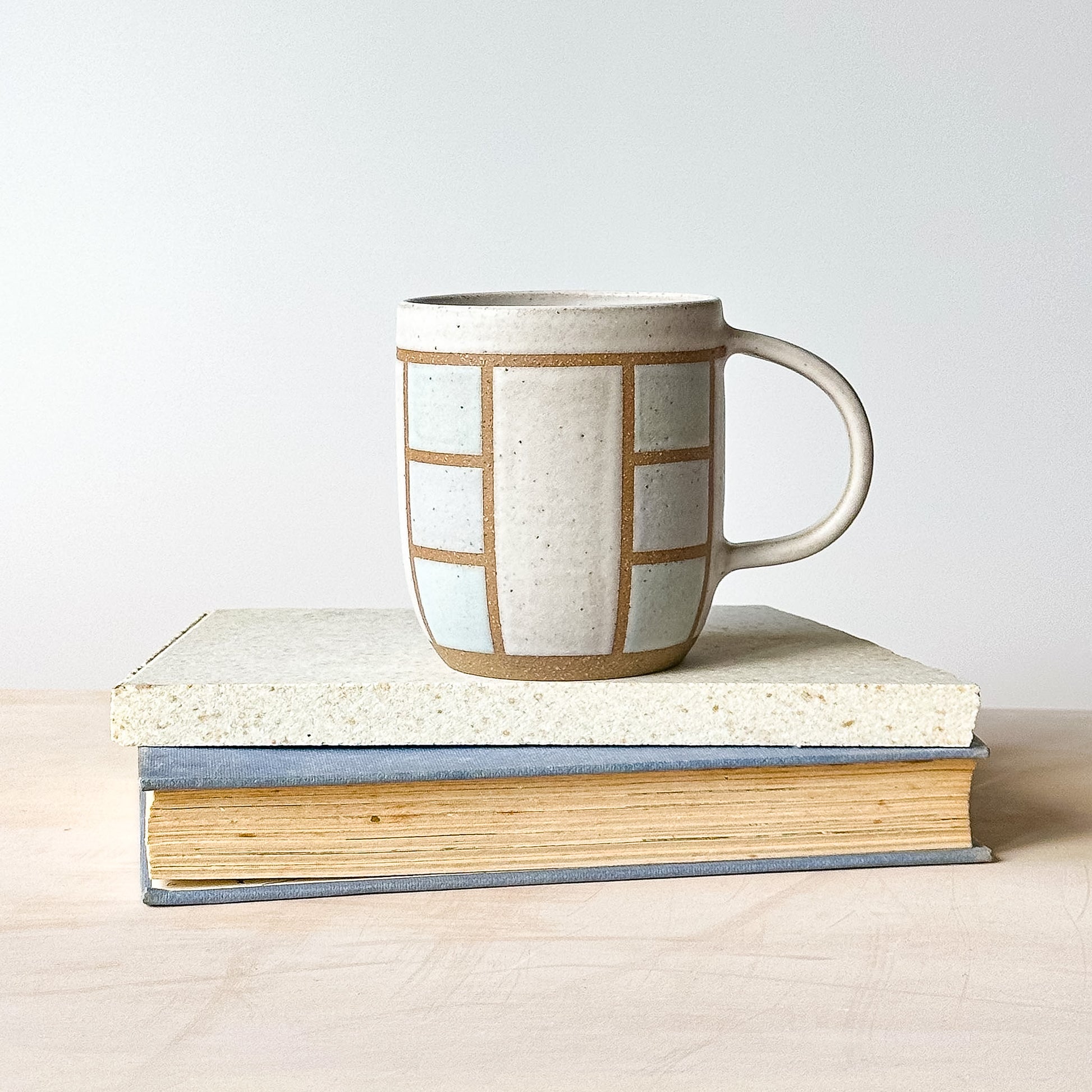 A geometric styled mug on a tile with a light background.