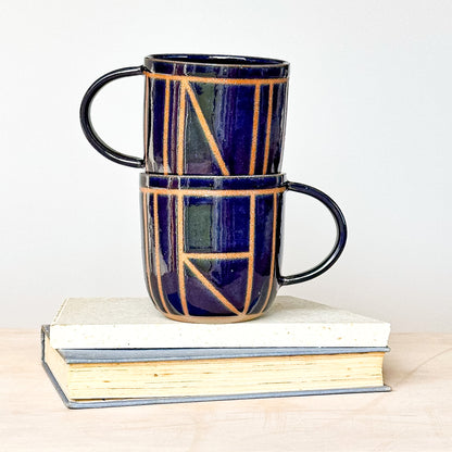 Two stacked ceramic mugs with geometric patterns on a white background