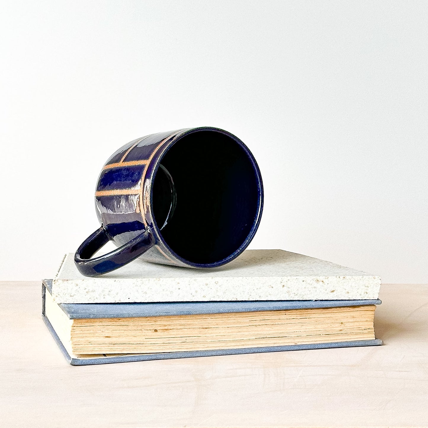 Blue mug on top of a book with a white background