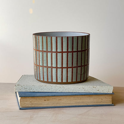Ceramic pot with striped design on top of a book