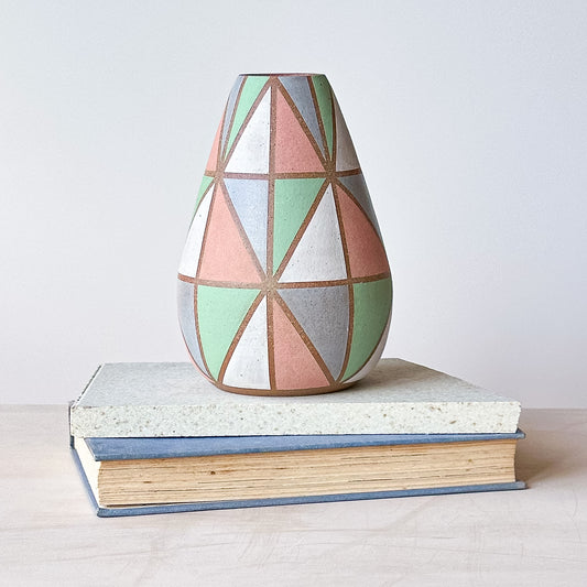 Geometric patterned vase on a stack of books with a plain background