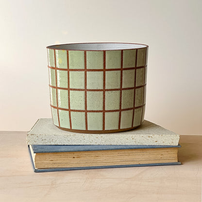 Ceramic planter with grid pattern on top of a book
