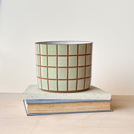 Ceramic planter with grid pattern on top of a book