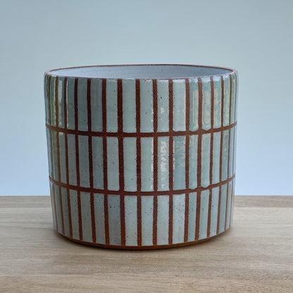 Ceramic pot with striped tile pattern on a wooden surface