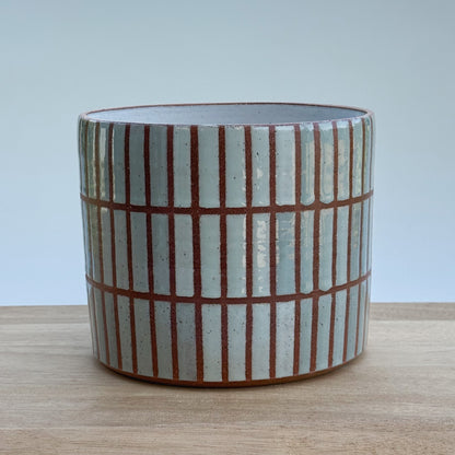 Ceramic pot with striped tiled pattern on a wooden surface
