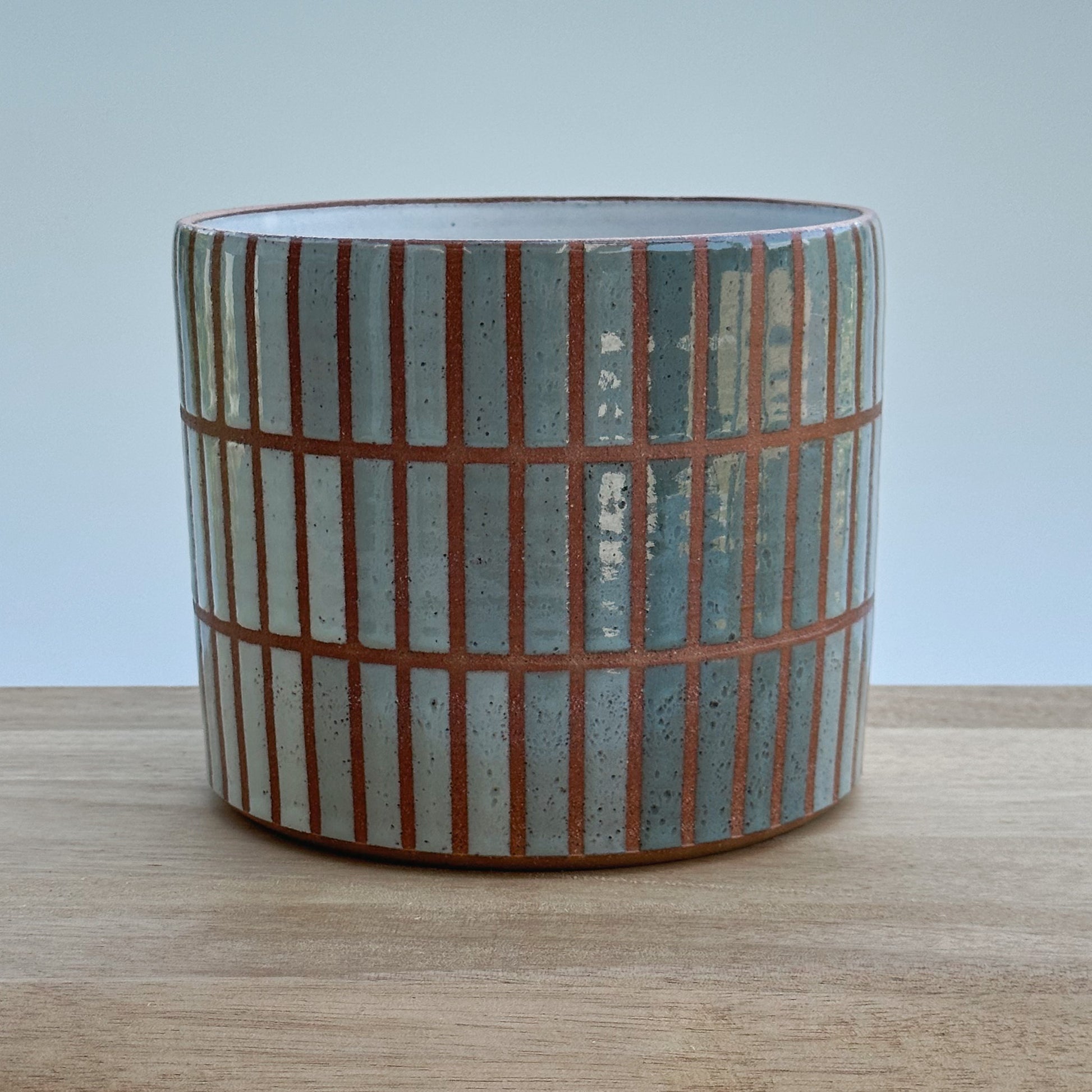 Ceramic planter with striped pattern on a wooden surface