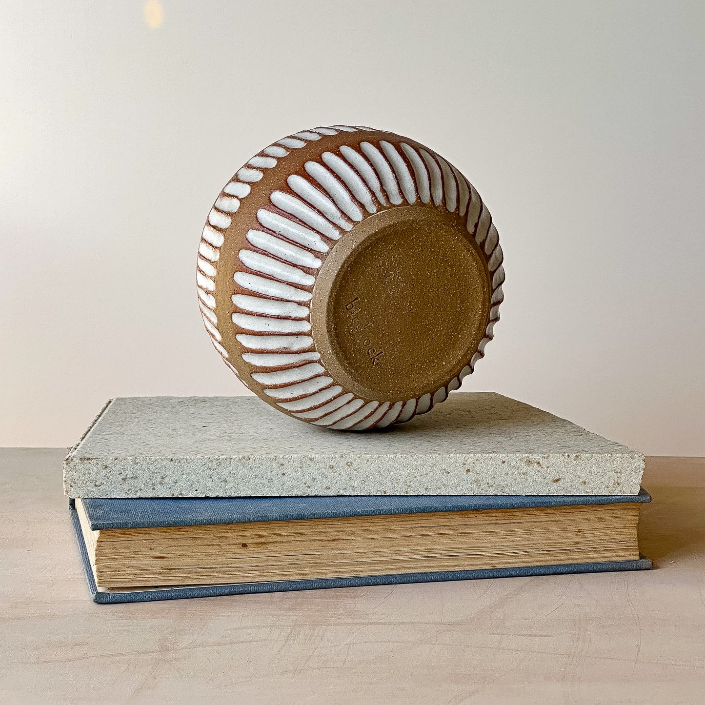 Ceramic bowl with wavy design on top of a book against a plain background
