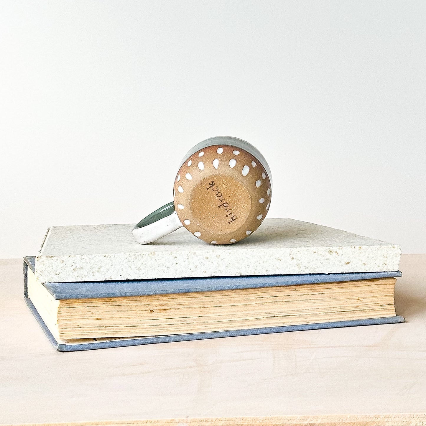 Espresso mug on its side, displaying the base on top of a stack of books