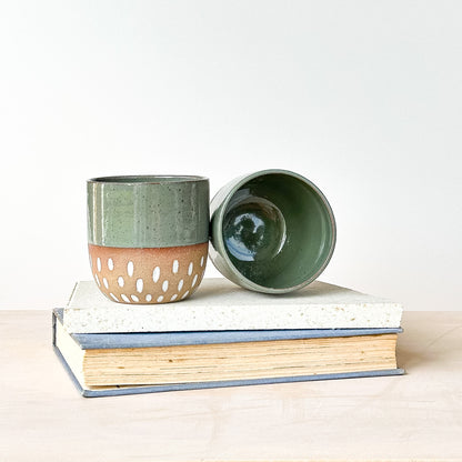 Two ceramic containers on top of books with a white background