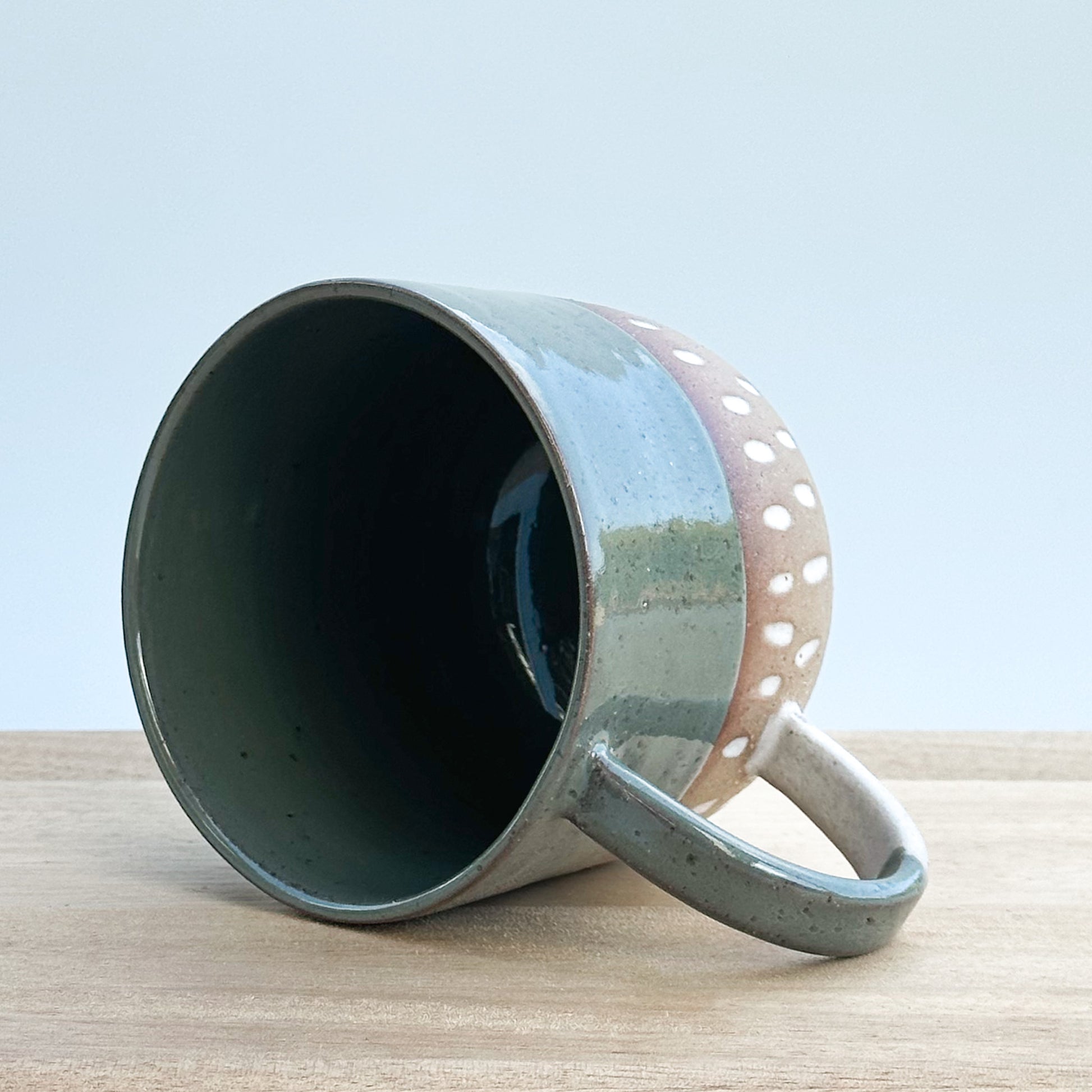 Ceramic mug with a handle on a wooden surface and a light background