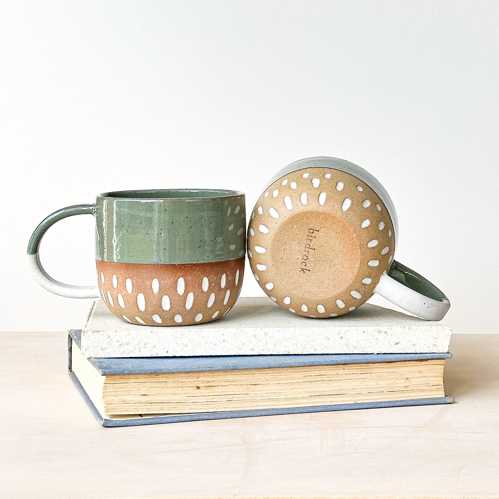 Ceramic mug with perforated design on a stack of books