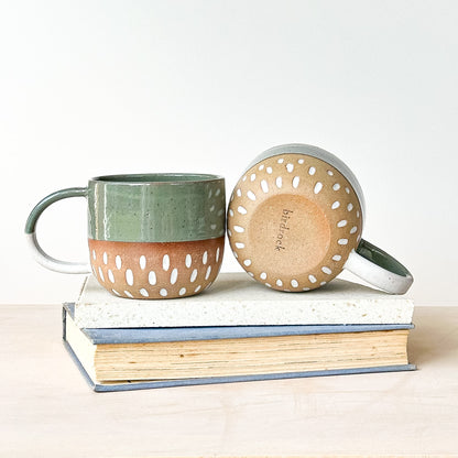 Ceramic mug with perforated design on a stack of books