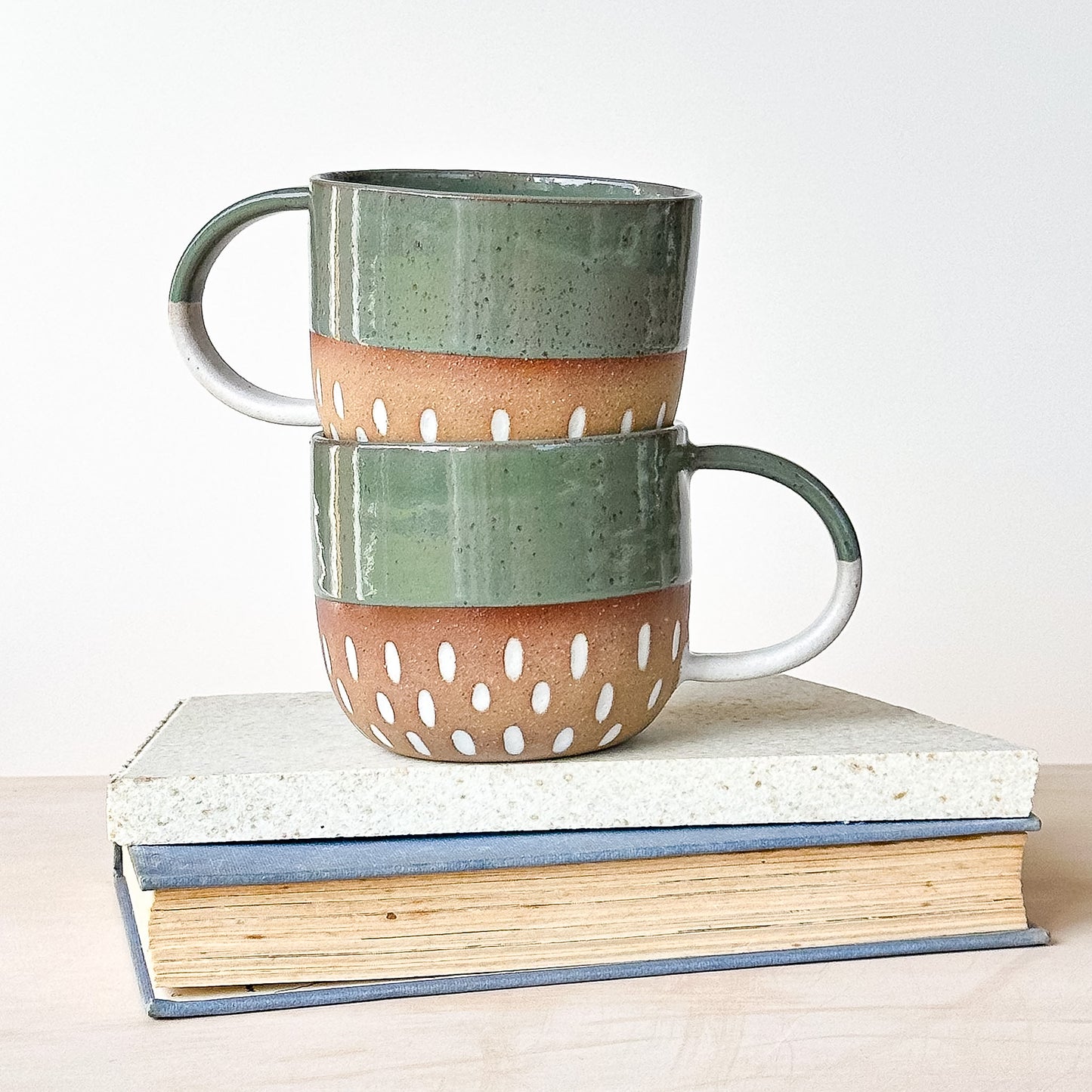 Two ceramic mugs stacked on top of each other with a white background