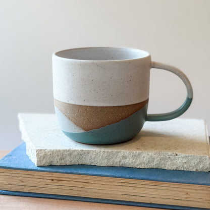 Ceramic mug with a coastal design on a tile and a book