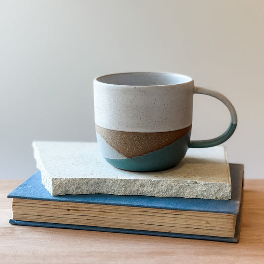 Ceramic mug with a coastal design on a tile and a book